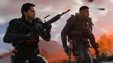 Two soldiers in tactical gear stand ready with weapons in a warzone.