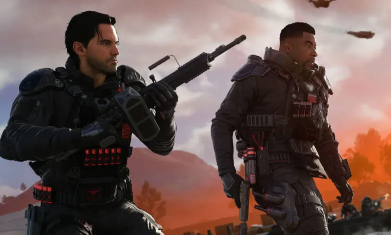 Two soldiers in tactical gear stand ready with weapons in a warzone.