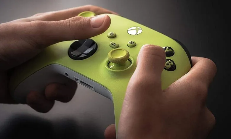 Hands hold a vibrant electric volt Xbox controller, ready for gaming.