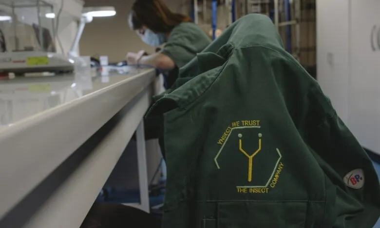Ynsect lab coat with worker in background, focused on research.