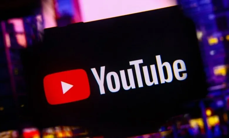 YouTube logo displayed on a screen with a blurred city background.