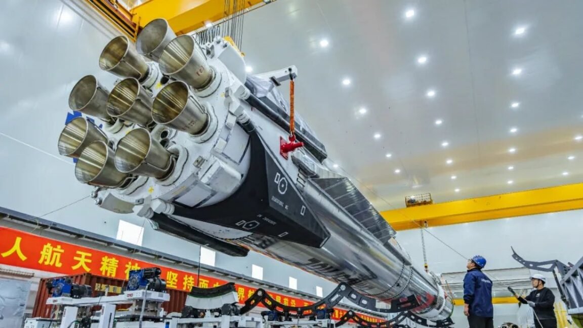 Rocket with multiple engines suspended in a large industrial facility.