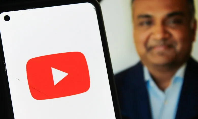 Smartphone displays YouTube logo with Neal Mohan's profile in background.