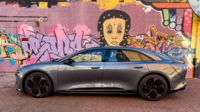 Gray Lucid Air Touring electric car parked against a colorful graffiti wall.