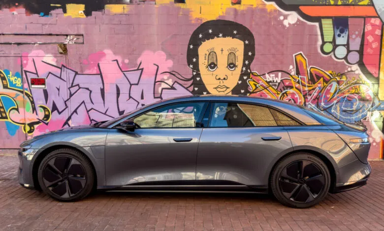 Gray Lucid Air Touring electric car parked against a colorful graffiti wall.