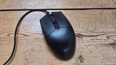 Black Corsair gaming mouse with braided cable on a wooden surface.