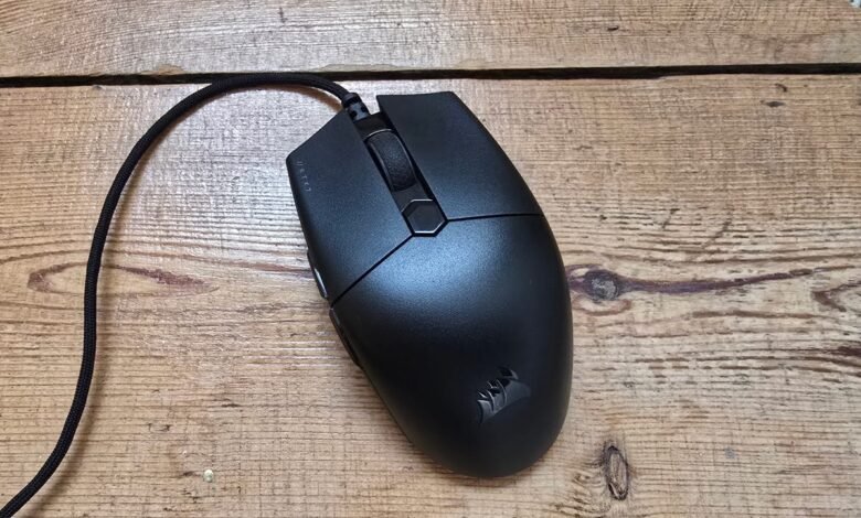 Black Corsair gaming mouse with braided cable on a wooden surface.