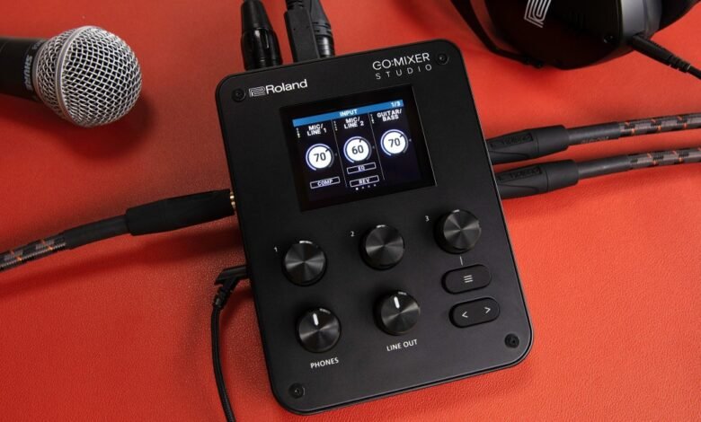 Roland Go:Mixer Studio audio interface with microphone and headphones on orange surface.