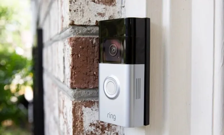 Ring video doorbell mounted on a white door frame next to a brick wall.