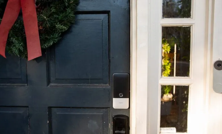 Dark blue front door with smart lock, wreath, glass panes, and doorbell.
