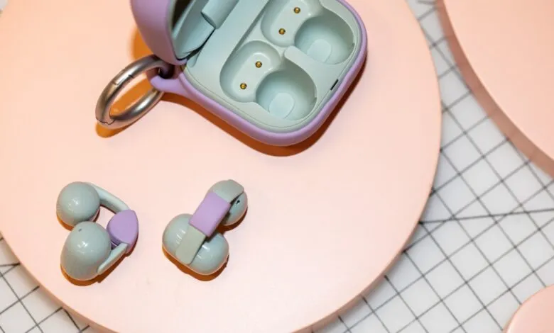 Sony Linkbuds with open charging case on pink surface.