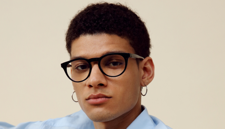 Portrait of a young man with glasses and hoop earrings.