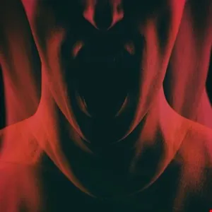 Abstract image of a person's neck and mouth in red tones, creating a distorted, screaming effect.