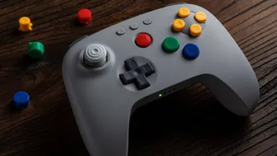Gray 8BitDo gamepad with colorful buttons on a wooden surface.