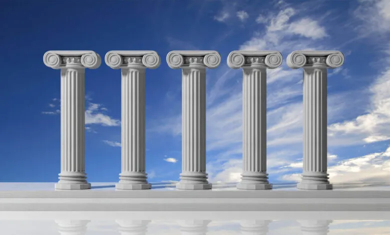 Five white Ionic columns stand against a blue sky with wispy clouds.