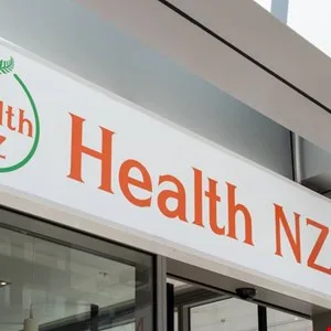 Health NZ signage with green leaf logo and orange text above a glass entrance.