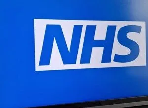 Laptop screen displays the NHS logo in white on a blue background.