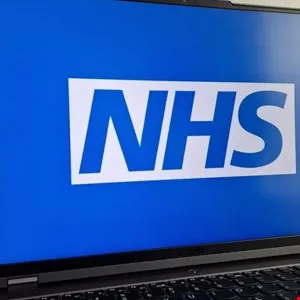 Laptop screen displays the NHS logo in white on a blue background.