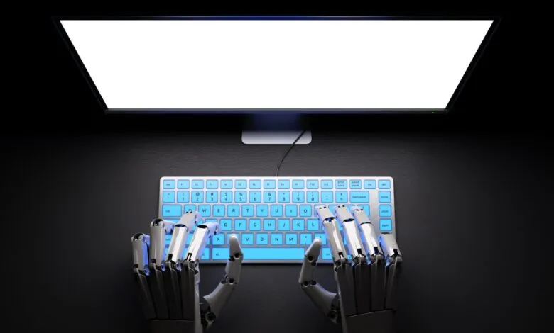 Robot hands type on a glowing keyboard in front of a blank monitor.