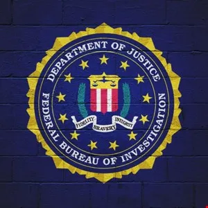 FBI seal painted on a dark blue brick wall, featuring stars and the words 'Fidelity, Bravery, Integrity'.