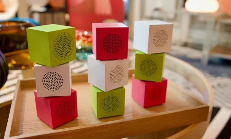 Colorful cube speakers stacked on a wooden tray, green, red, and white.