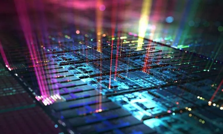 Close-up of a microchip with colorful light beams shining on its surface.