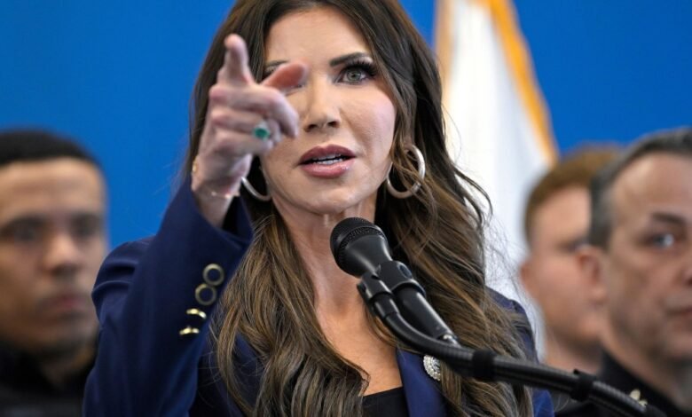 Kristi Noem points during a press conference, wearing a blue blazer.