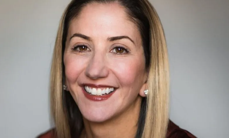 Close-up portrait of a smiling woman with blonde hair and brown eyes.
