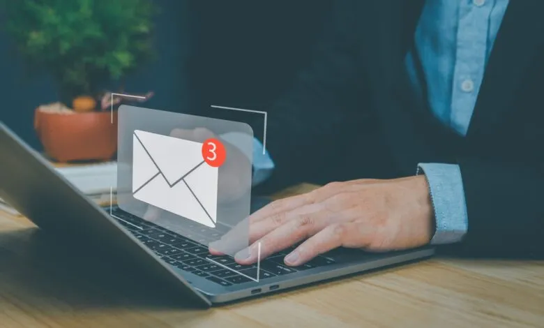 Person types on laptop with email notification icon showing 3 unread messages.