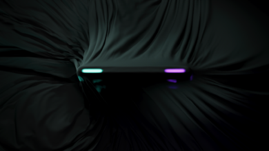 Sleek black device partially covered by dark fabric, neon lights visible.