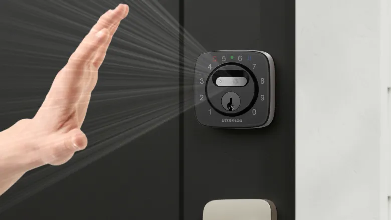 Hand approaching smart lock with keypad on dark door.