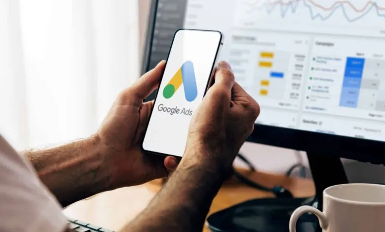 Person holds phone displaying Google Ads logo, data on screen.