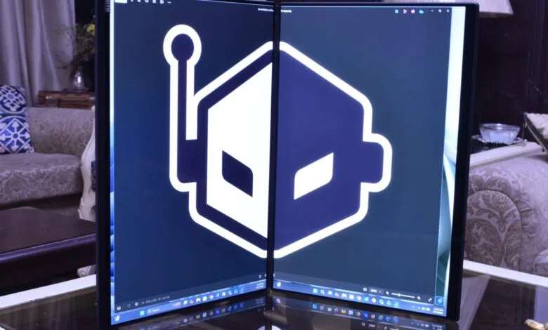 Foldable dual-screen laptop displaying a white robot logo on a dark blue background.