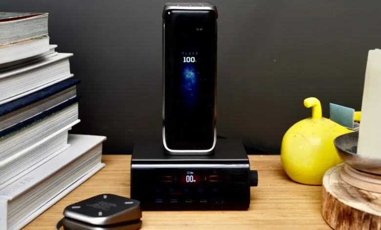 Black smartphone charging on a dock, surrounded by books and decor.