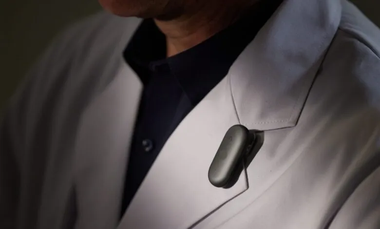 Close-up of a doctor's lab coat with a black clip-on device.