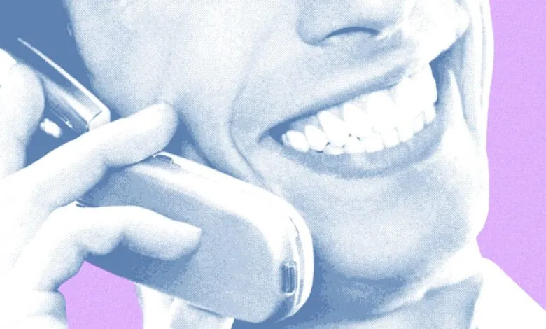 Close-up of person smiling while talking on a retro cell phone.