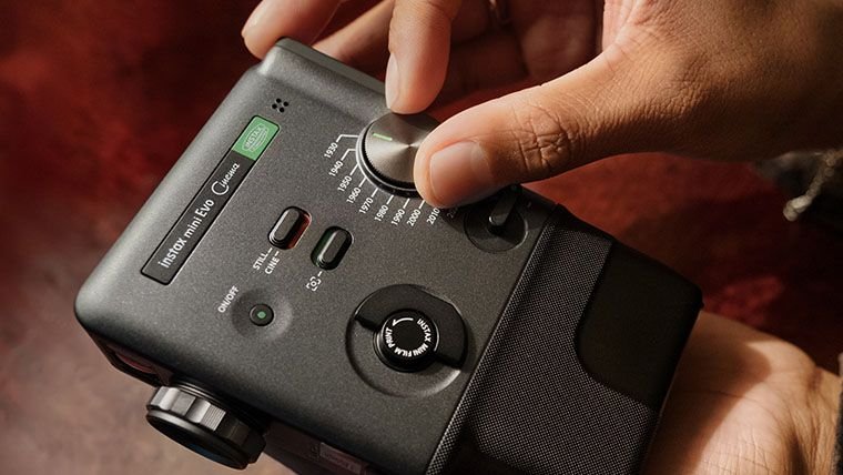 Hand adjusts the dial on an Instax Mini Evo Cinema camera.