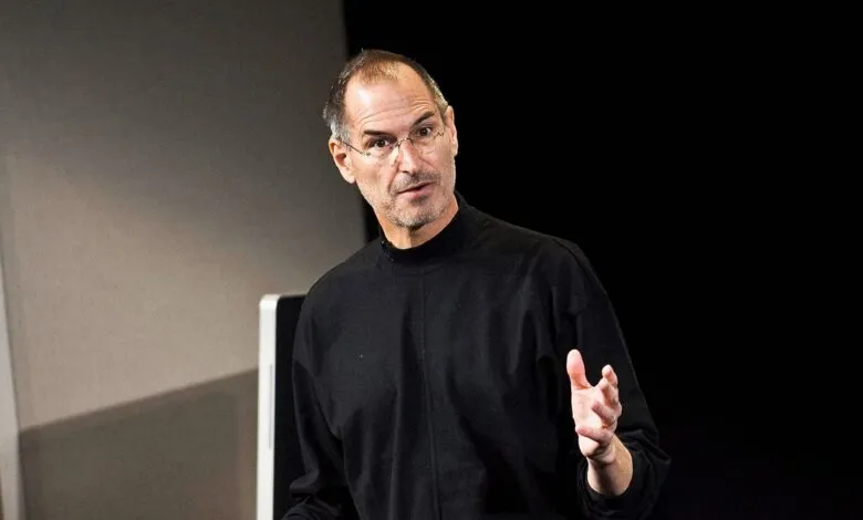 Steve Jobs in black turtleneck gesturing during a presentation.