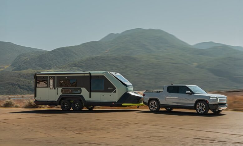 Rivian truck towing an Evotrex camper trailer against a mountain backdrop.