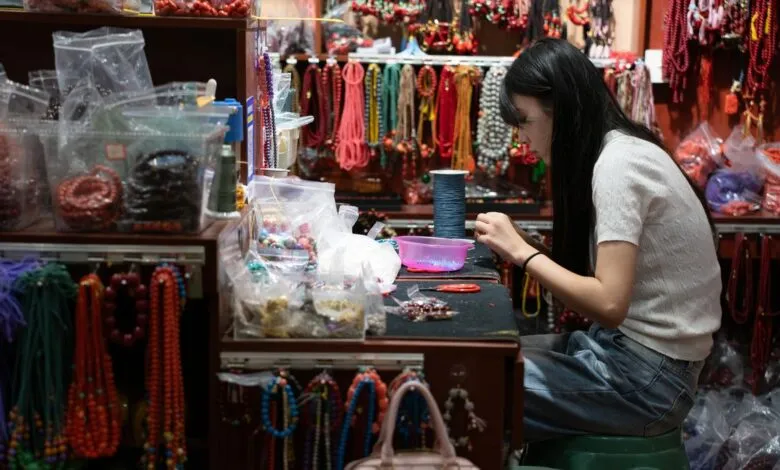 Woman crafting jewelry in a vibrant bead shop setting.