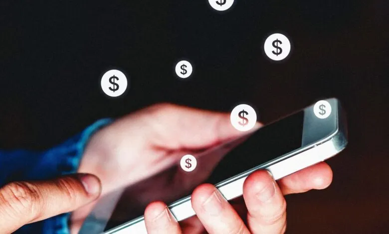 Hand holding phone with dollar signs floating, suggesting online earnings.