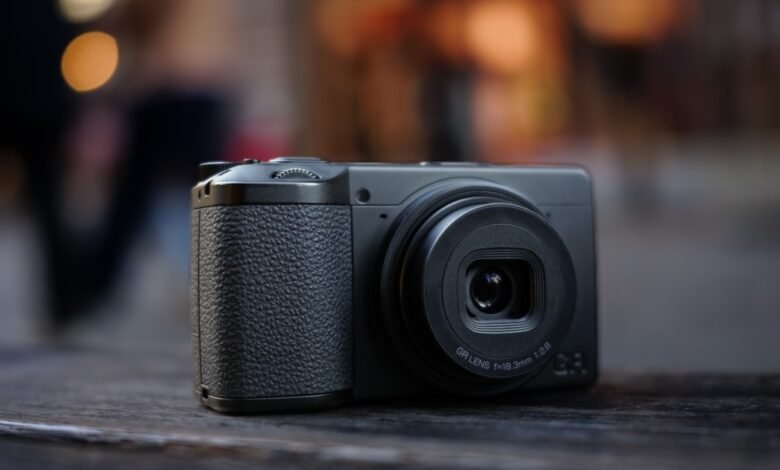 Close-up of a Ricoh GR IIIx camera on a wooden surface.