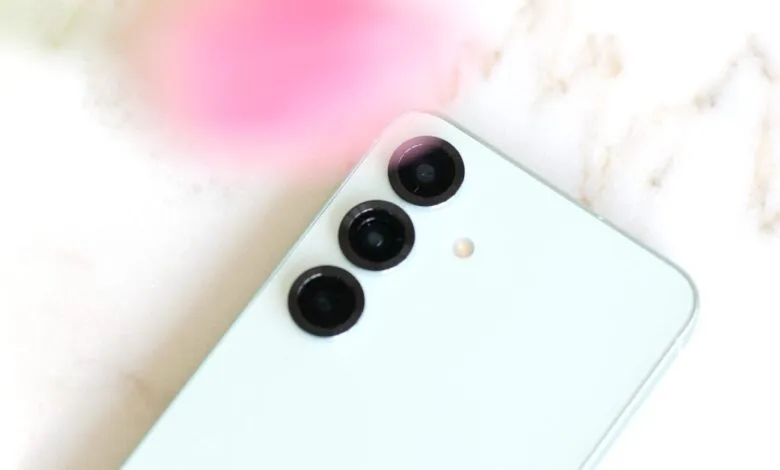 Close-up of a light blue smartphone with a triple-lens camera system.