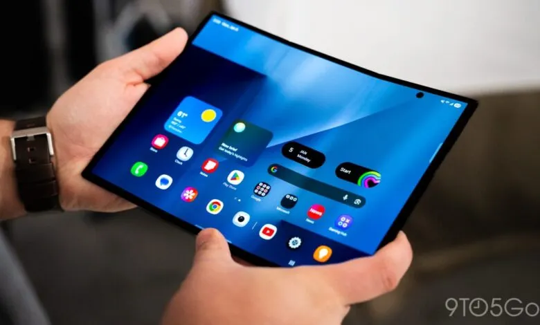 Hands hold a large foldable tablet displaying a modern, colorful interface.