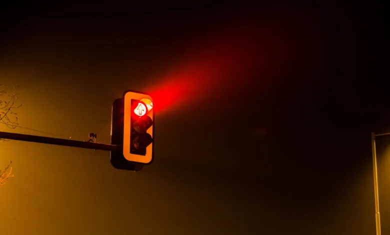 Illuminated red traffic light at night with arrow pointing up.