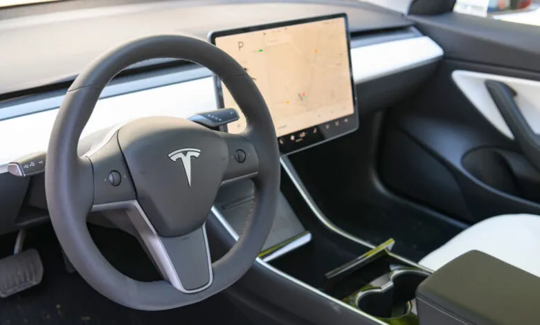 Tesla Model 3 interior featuring steering wheel and touchscreen display.