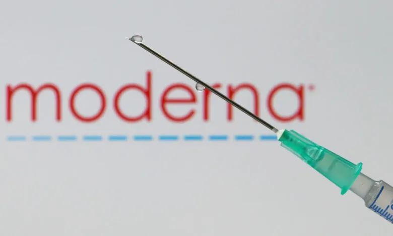 Syringe with droplet in front of the Moderna logo.