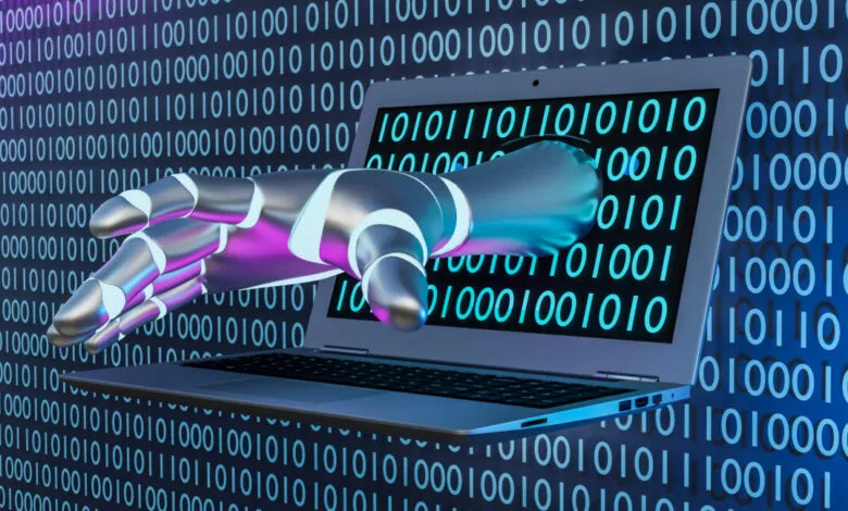 Metallic robot hand extends from laptop screen with binary code background.