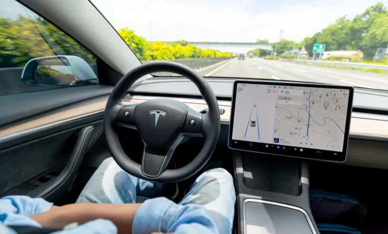 Interior view of Tesla car using autopilot on highway.