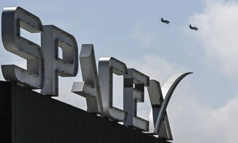 SpaceX sign with two fighter jets flying in the sky above.